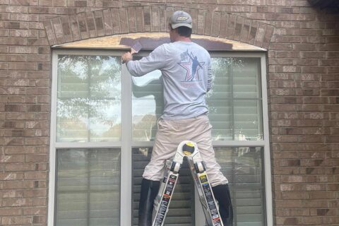 man painting trim around newly installed window