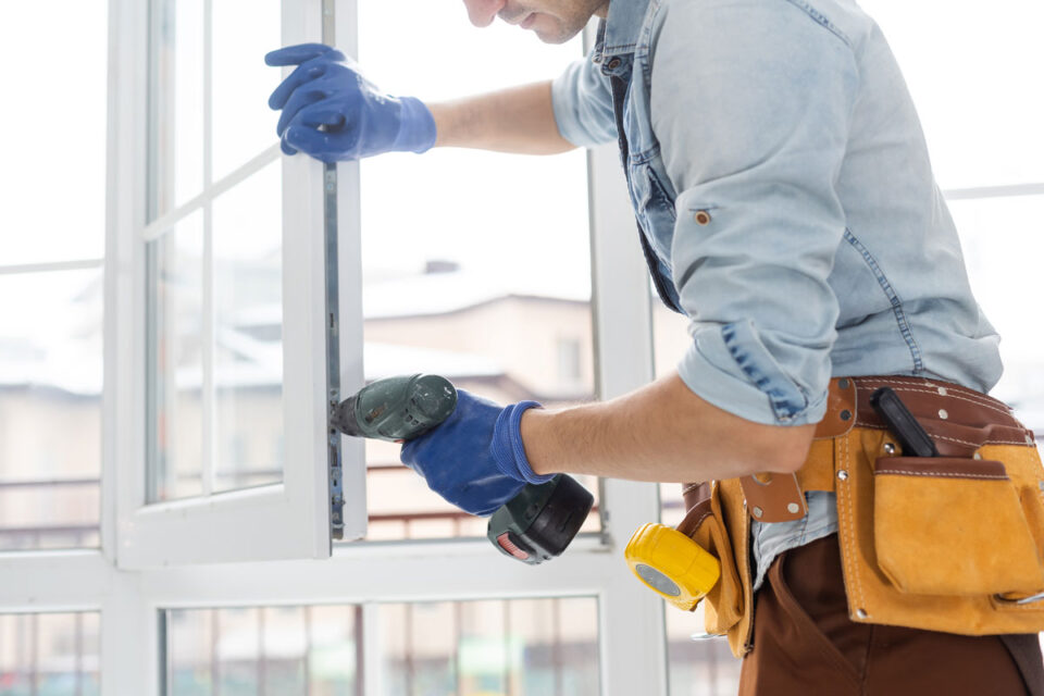 Construction worker installing window in house